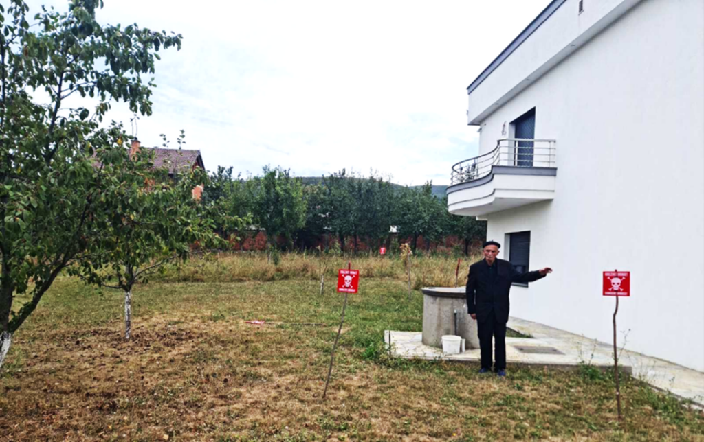 Man standing in front of white house where HALO Trust and Schonstedt found a buried cluster bomb